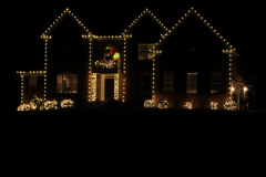 Custom-designed holiday lighting display — roofline lights and wreaths creating a bright, cheerful holiday atmosphere